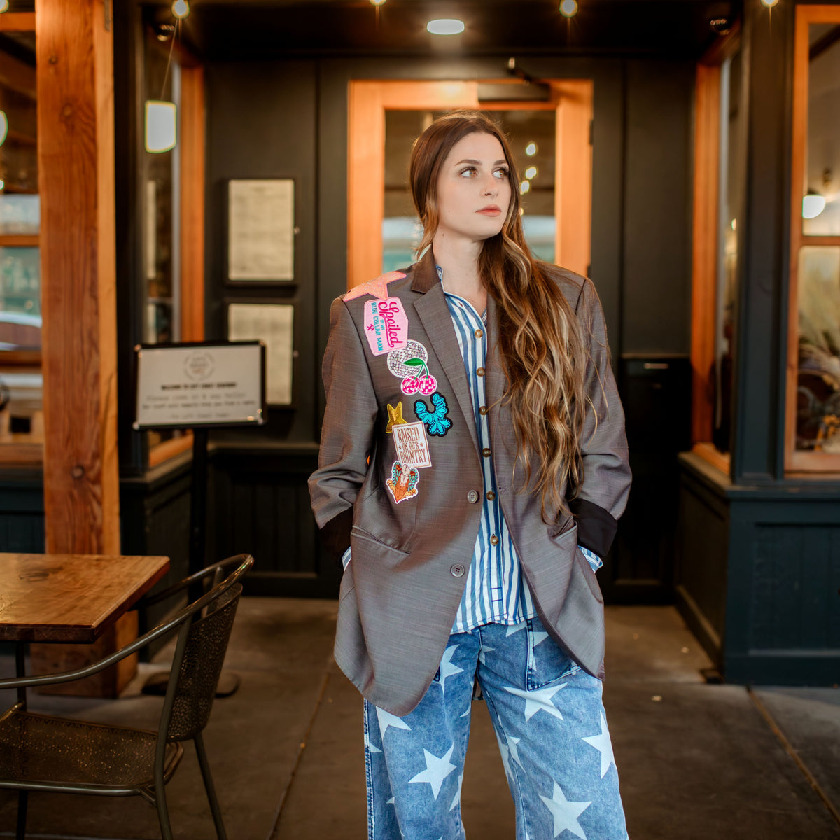Woman standing in a restaurant with wooden tables and chairs.