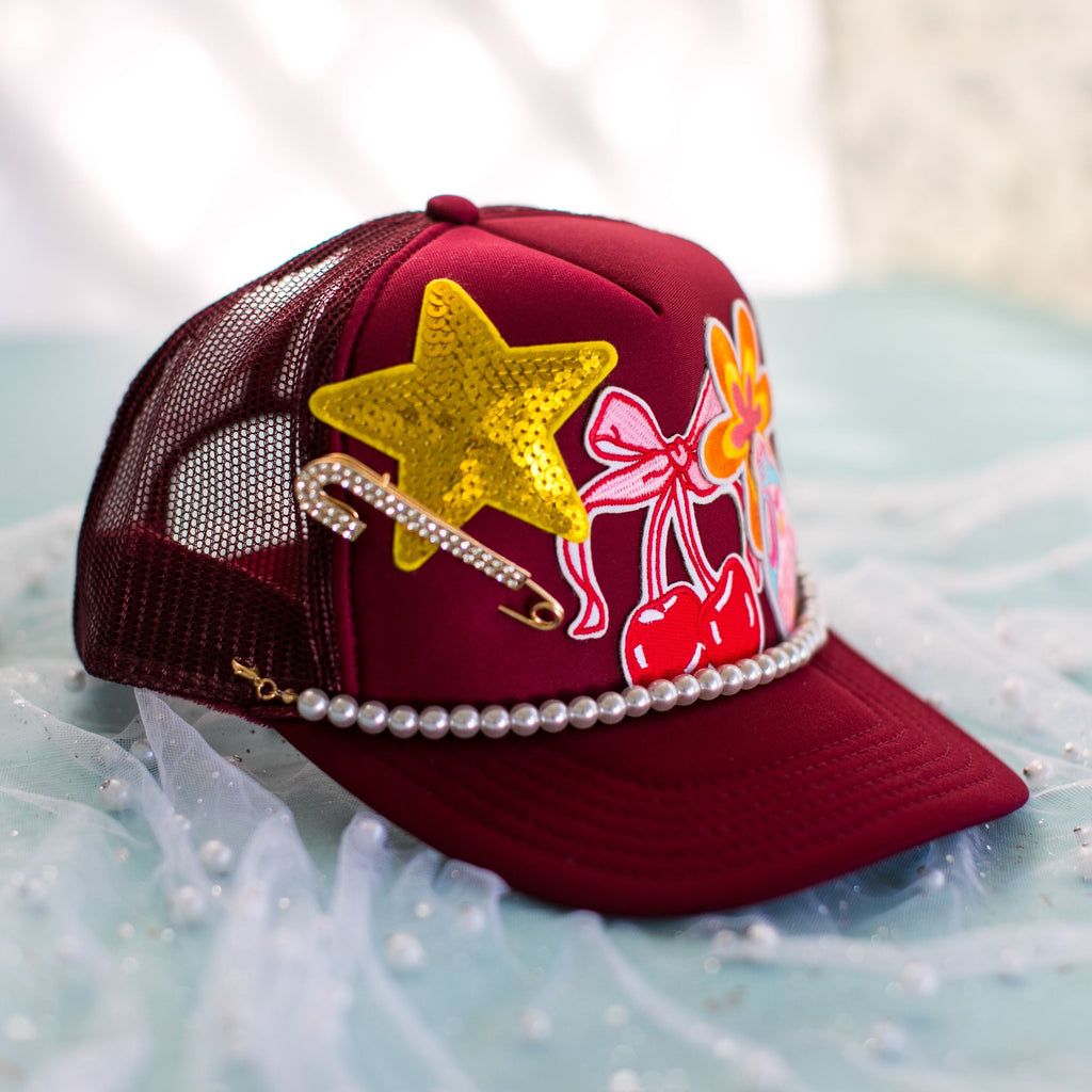 Maroon cap with colorful decorations on a light blue surface