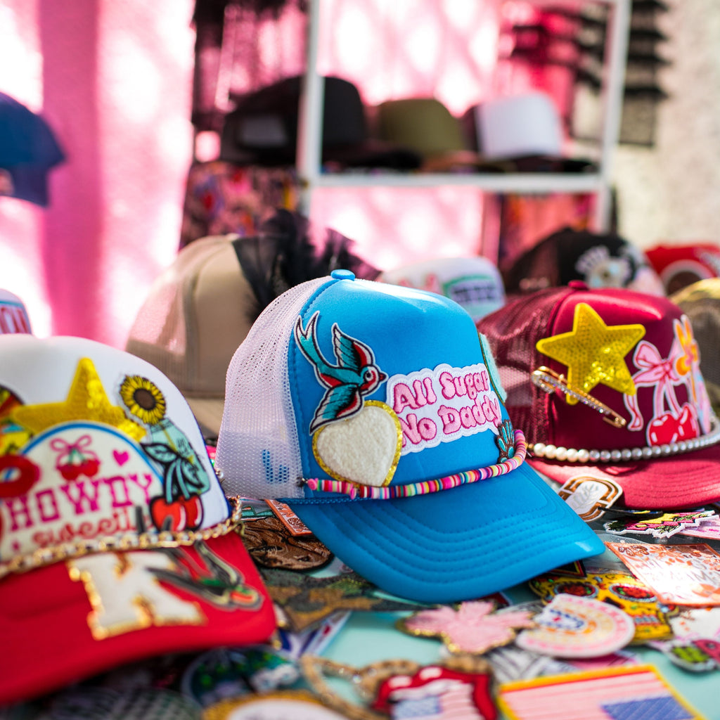 Colorful hats with various designs on a table with a pink background