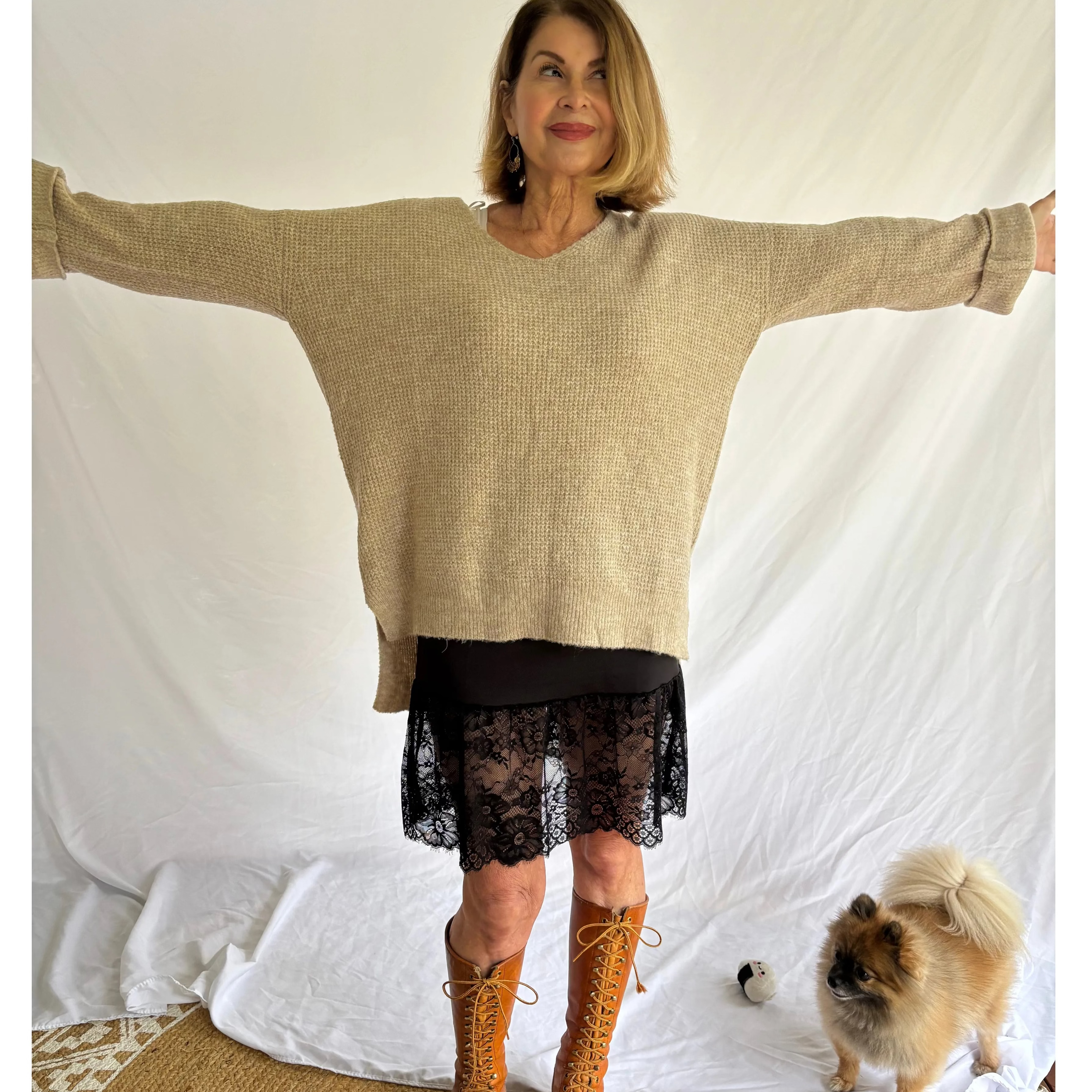 Woman wearing a beige sweater and brown boots with a dog on a white background