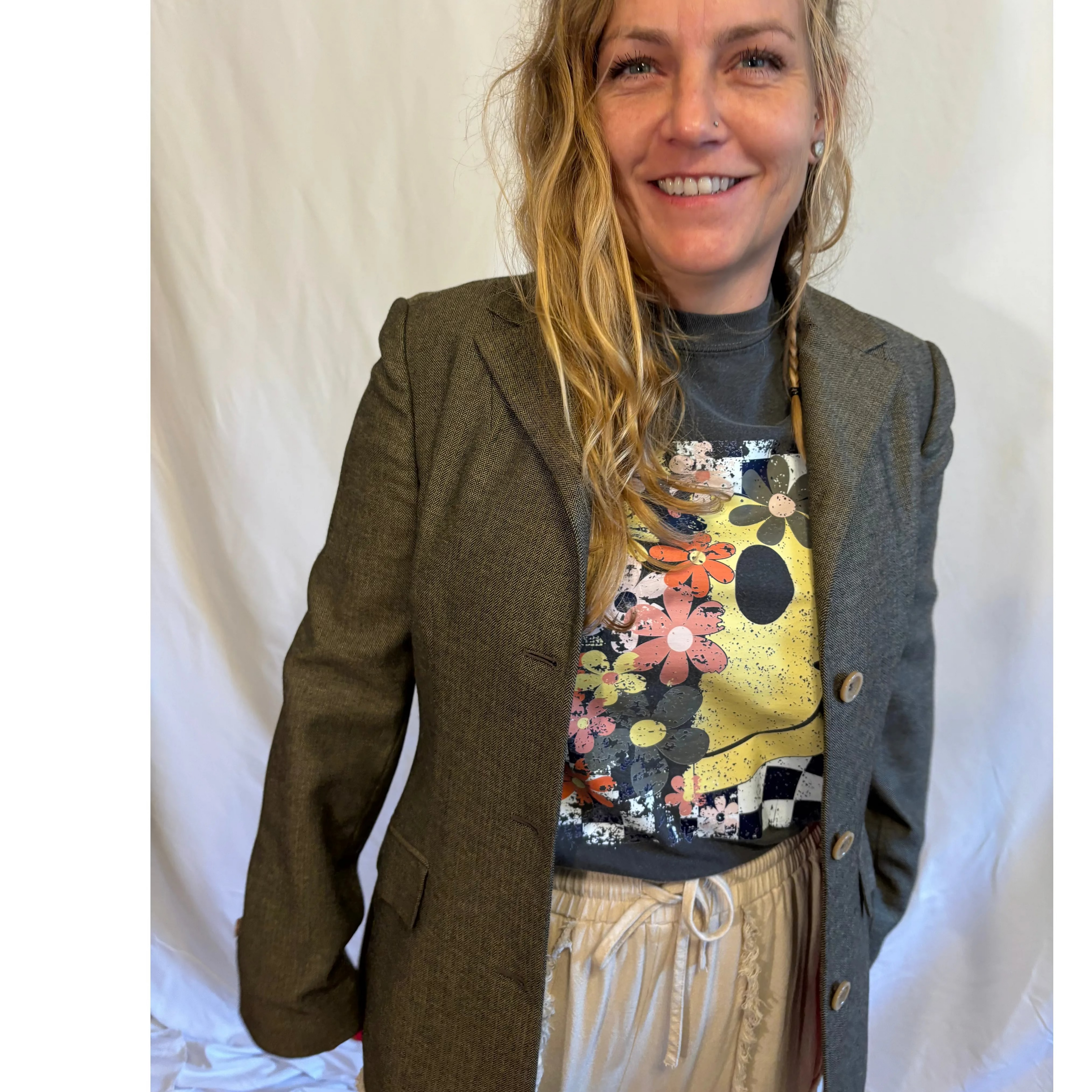 Woman wearing a brown blazer over a colorful graphic t-shirt with a white background