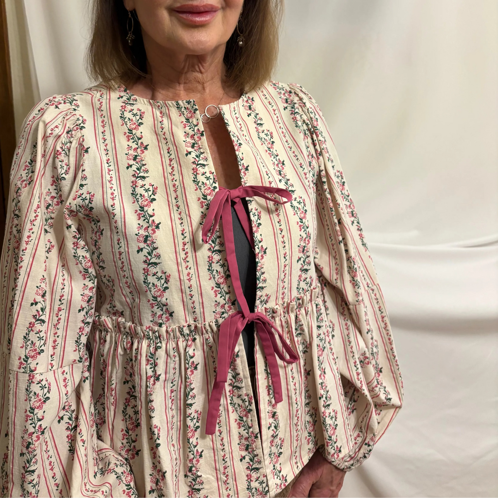 Woman wearing a floral dress with a pink bow against a plain background