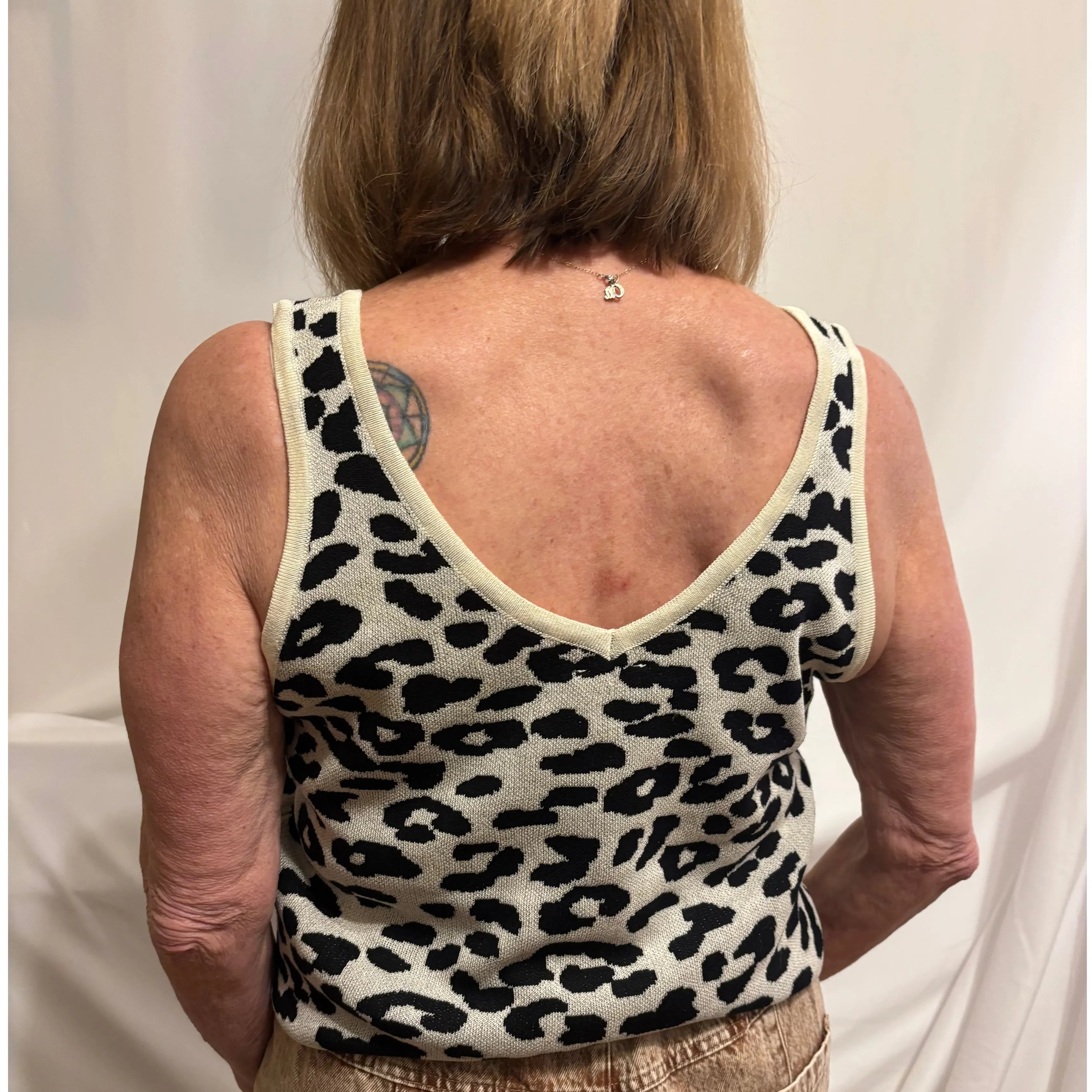 Person wearing a leopard print tank top against a plain background