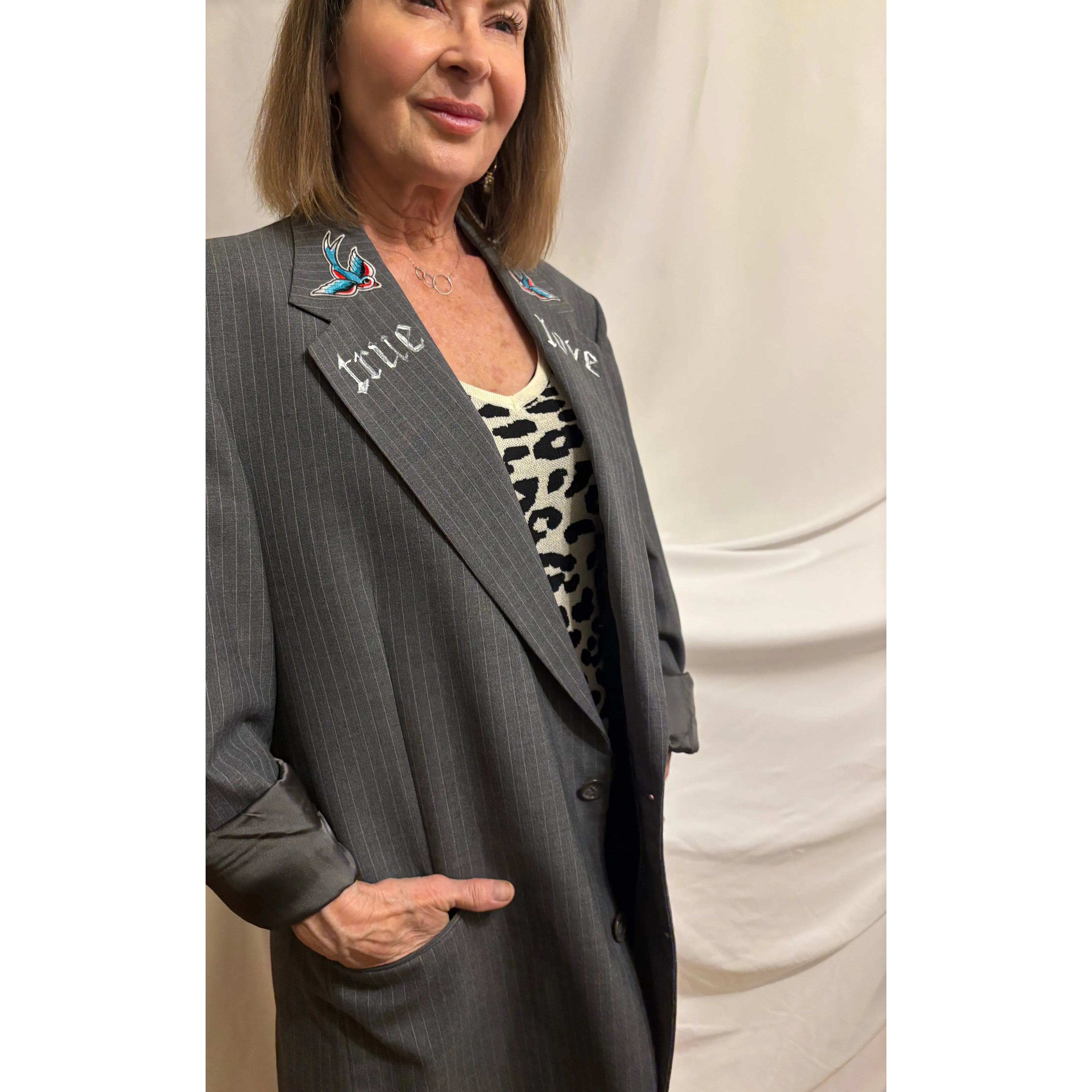 Woman wearing a gray pinstripe suit with decorative buttons against a white background
