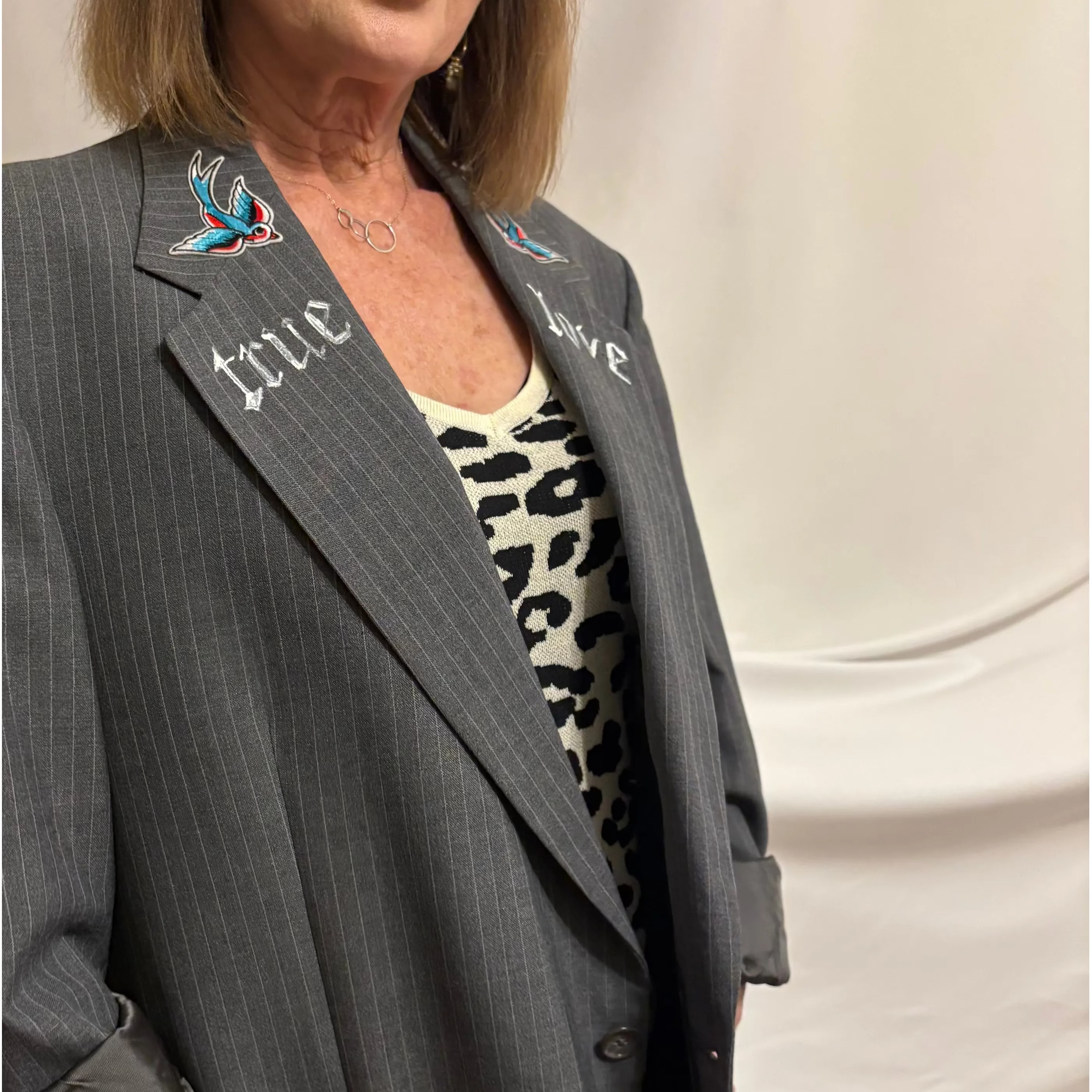 Woman wearing a gray pinstripe suit with decorative buttons against a white background