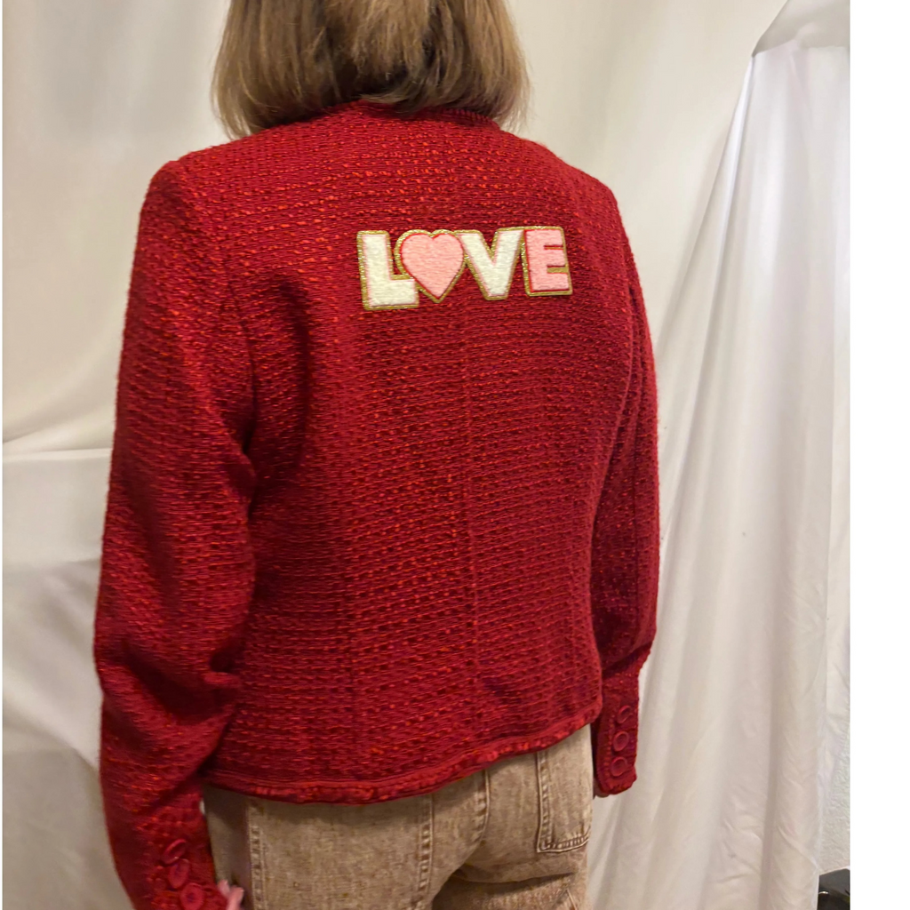 Person wearing a red sweater with 'LOVE' printed on the back against a white background
