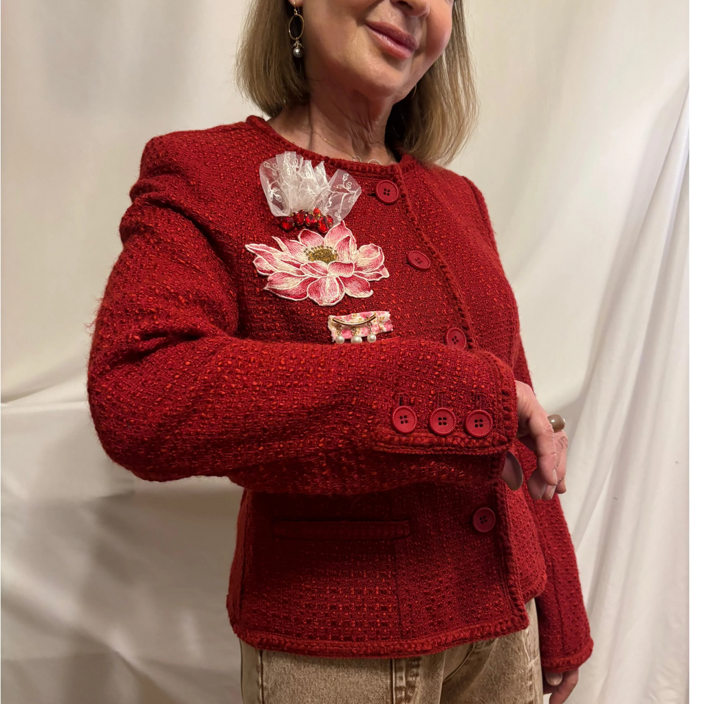 Woman wearing a red knitted cardigan with floral embroidery against a white background