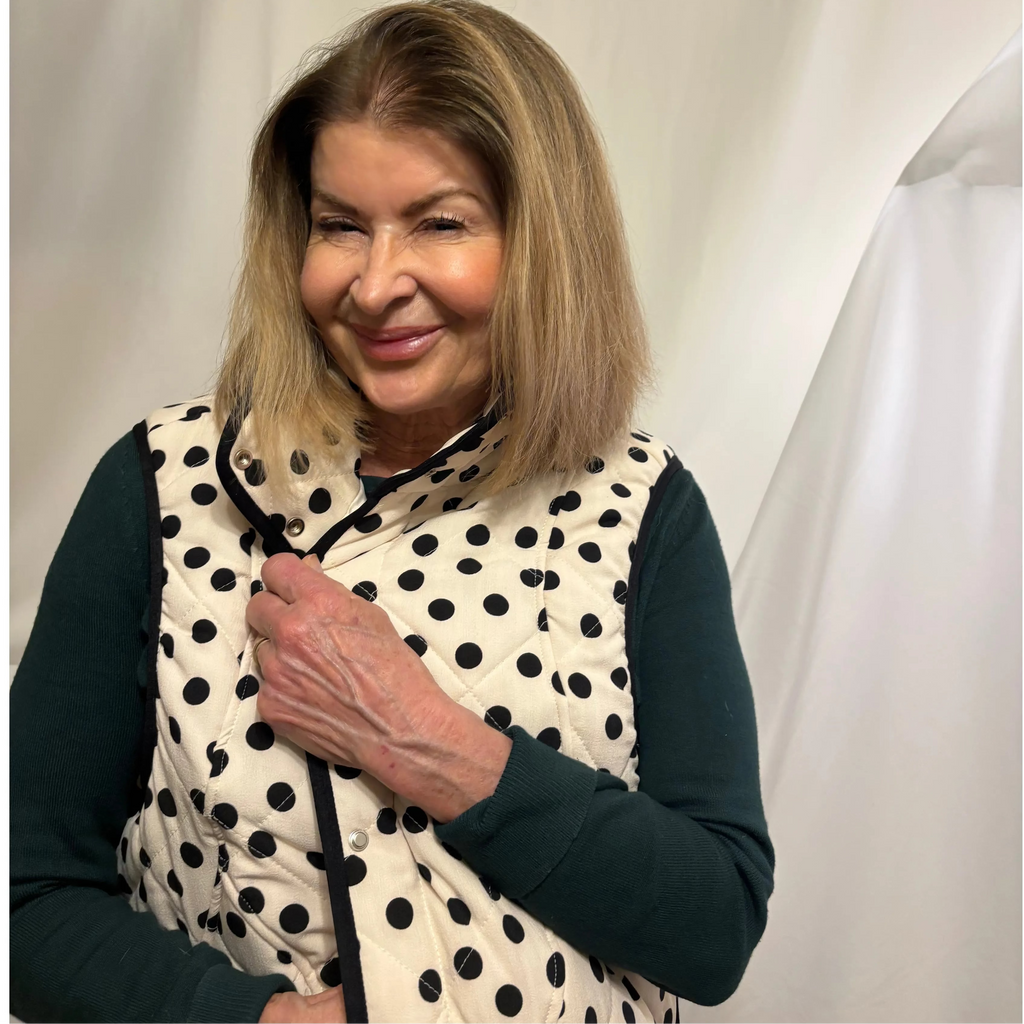 Woman wearing a polka dot vest against a plain background