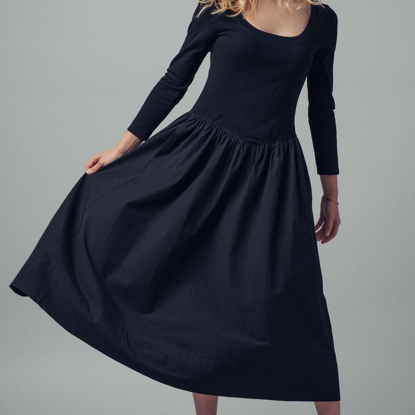 Woman wearing a black dress against a gray background