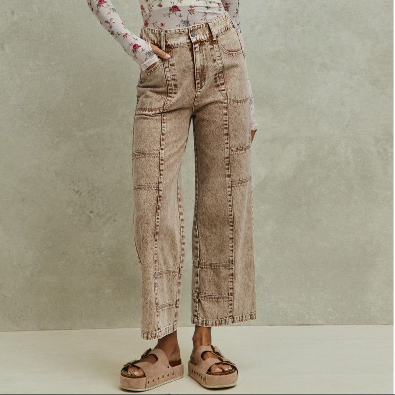 Woman wearing a floral top and beige wide-leg pants against a neutral background
