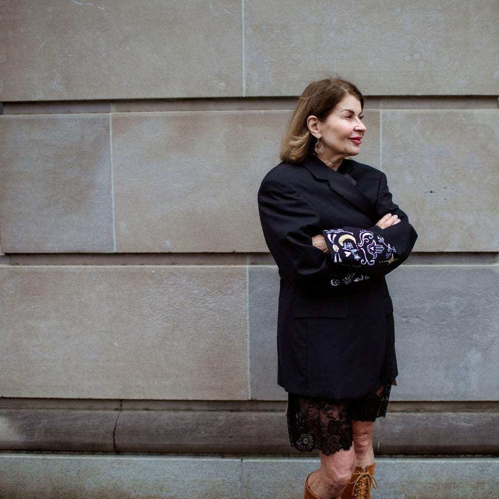 Woman standing against a stone wall with a building in the background