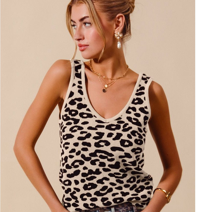 Woman wearing a leopard print tank top and denim shorts against a beige background